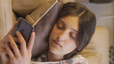 Vertical-video-of-Young-woman-falling-asleep-at-night-with-phone-in-hand.-Phone-addiction.